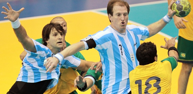 Jogador argentino tenta superar marcação de três brasileiros na decisão do handebol