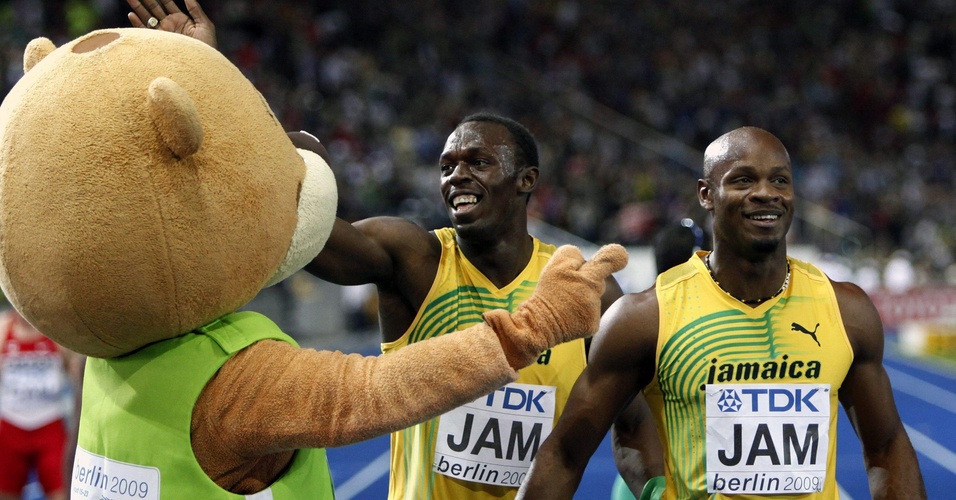 Asafa Powell (d) e Usain Bolt brincam com o mascote do Mundial de Atletismo de 2009, após vencerem o 4 x 100 m rasos na competição, em Berlim