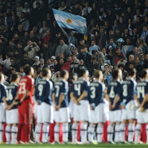 Torcedora argentina ergue a bandeira do país enquanto é tocado o hino antes de jogo - AFP PHOTO / EITAN ABRAMOVICH