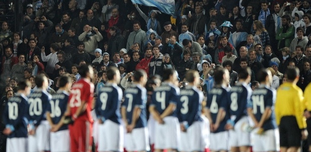 Torcedora argentina ergue a bandeira do país enquanto é tocado o hino antes de jogo - AFP PHOTO / EITAN ABRAMOVICH