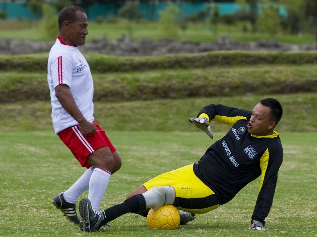 Ex-jogador colombiano Willintong Ortiz tenta passar pelo goleiro Valencia durante amistoso contra time formado por vítimas de minas terrestres, em evento organizado para promover o Mundial Sub-20 em Bogotá - Luis Acosta/AFP