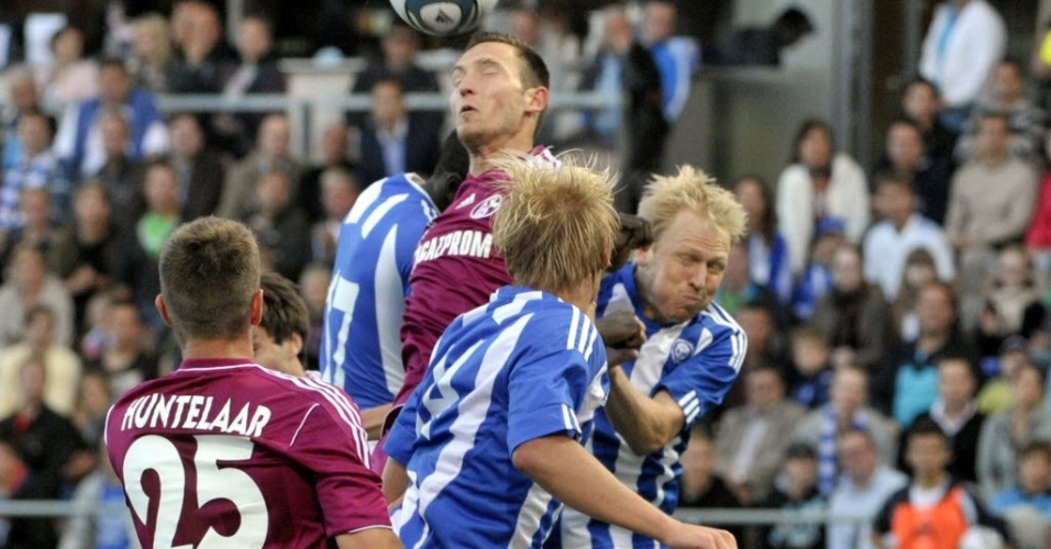 Benedikt Hoewedes, do Schalke 04, sobe mais alto do que três adversários do Helsinki e cabeceia a bola, pela Liga Europa