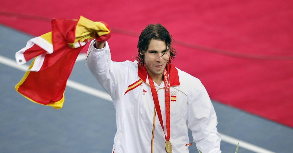 O tenista Rafael Nadal comemora com a bandeira da Espanha e sua medalha de ouro após vencer o chileno Fernando González, em Pequim