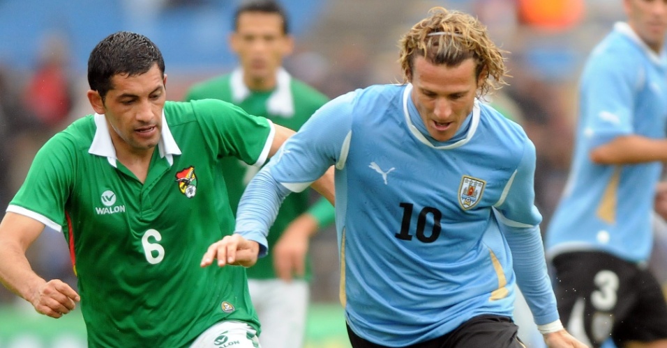 Forlán é perseguido por Flores no jogo entre as seleções do Uruguai e Bolívia, em Montevidéu
