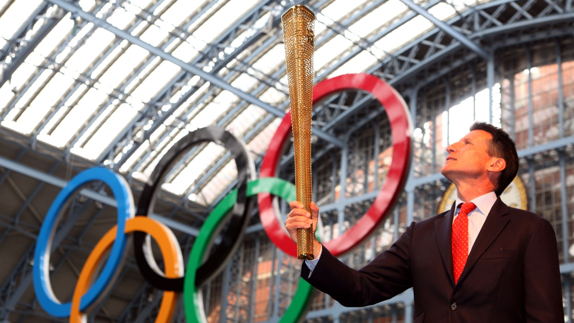 Sebastian Coe, chefe do Comitê Organizador da Olimpíada de 2012, posa com a tocha olímpica em londres (8/6/2011