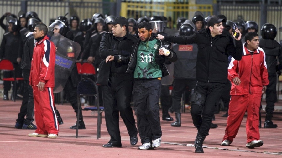 Policial socorre torcedor ferido após briga dos fãs do Al Ahly e do Al-Masry no Egito - REUTERS/Stringer