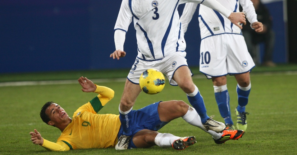 Atacante Leandro Damião cai em disputa de bola com jogador da Bósnia