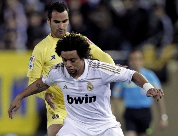 21.mar.2012 - O brasileiro Marcelo, do Real Madrid, protege a bola de Ángel López, do Villarreal, durante empate entre as equipes