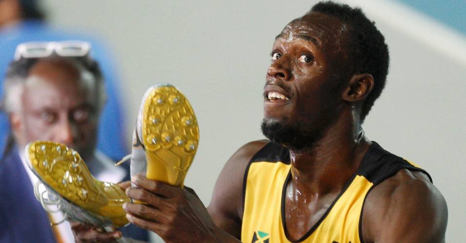 Usain Bolt exibe suas sapatilhas fazendo piada após a semifinal dos 200m em Daegu (02/09/2011)