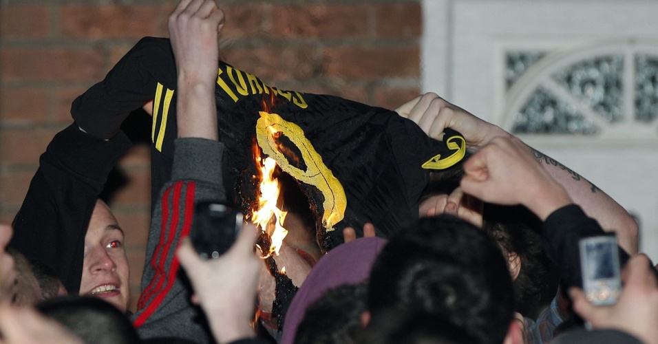 Torcedores do Liverpool queimam camisa de Fernando Torres em frente ao centro de treinamento do clube após negociação com o Chelsea
