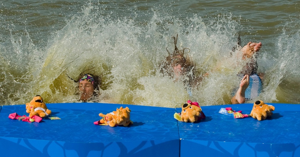 Remadoras argentinas mergulham na água após receberem medalha de ouro no pódio do Pan (19/10/2011)
