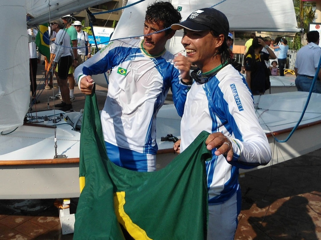 Gabriel Borges, o Coveiro, e Alexandre Tinoco comemoram com a bandeira brasileira após o ouro na classe Snipe do Pan (23/10/2011)